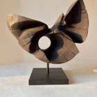 trace-of-fire-walnut-sculpture-in-hand-sunlight Hand-carved walnut wood sculpture “Trace of Fire” held in hands in warm sunlight, abstract organic form with natural cracks and circular opening.