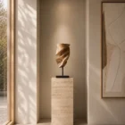 Breath of Fire hand-carved walnut wood sculpture displayed on a travertine pedestal in a contemporary gallery-inspired interior