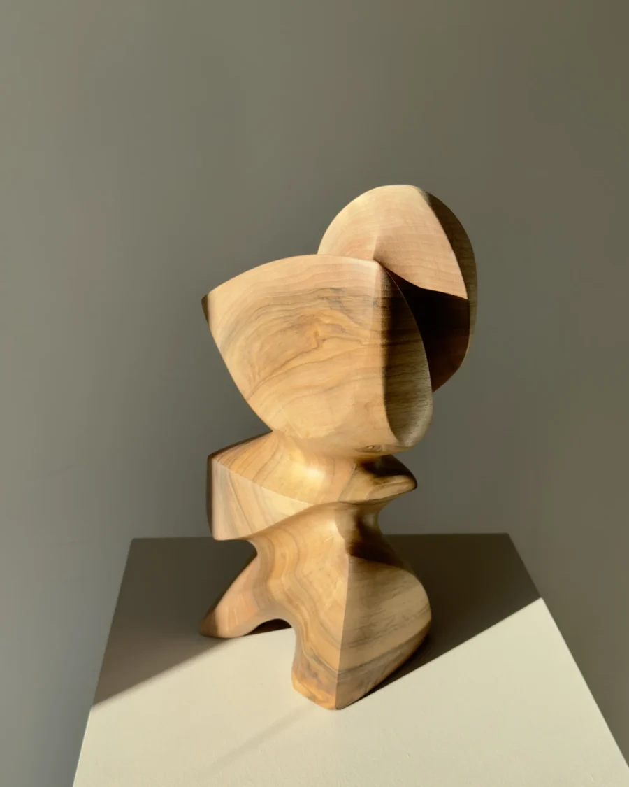 Three-quarter view of Aureon abstract wood sculpture showing light, shadow, natural walnut grain and balanced organic form.