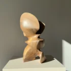 Side view of Aureon abstract walnut sculpture in sunlight, highlighting curved planes, shadows and warm walnut tones.