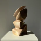 Side profile of Aureon walnut wood sculpture emphasizing its curved upper form, carved opening and smooth finish.
