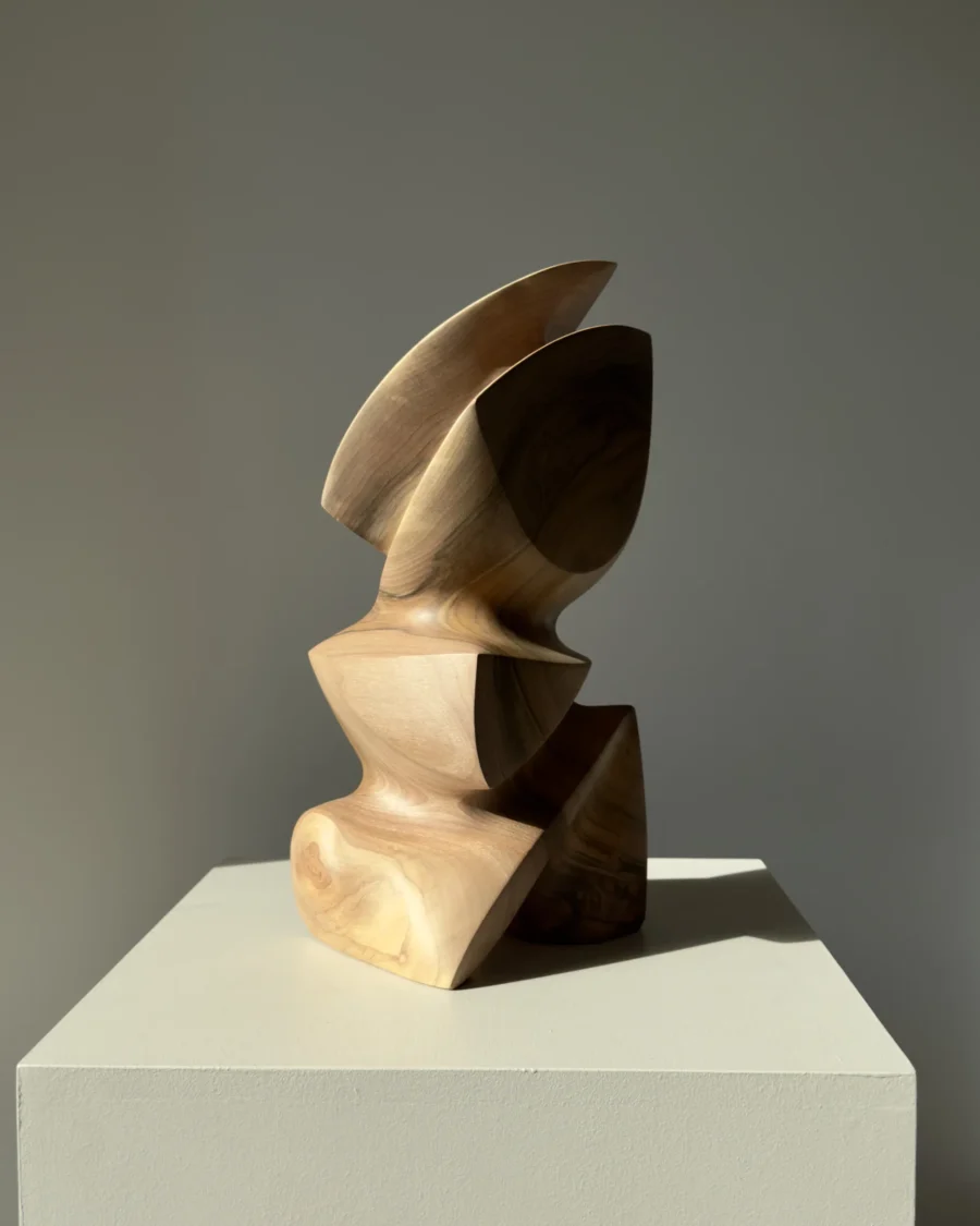 Side profile of Aureon walnut wood sculpture emphasizing its curved upper form, carved opening and smooth finish.