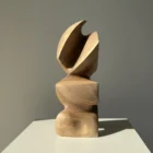 Abstract walnut wood sculpture Aureon standing on a white pedestal, showing its balanced vertical form and natural grain.