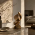 Aureon hand-carved walnut wood sculpture displayed in a warm organic modern interior with natural light and travertine console.