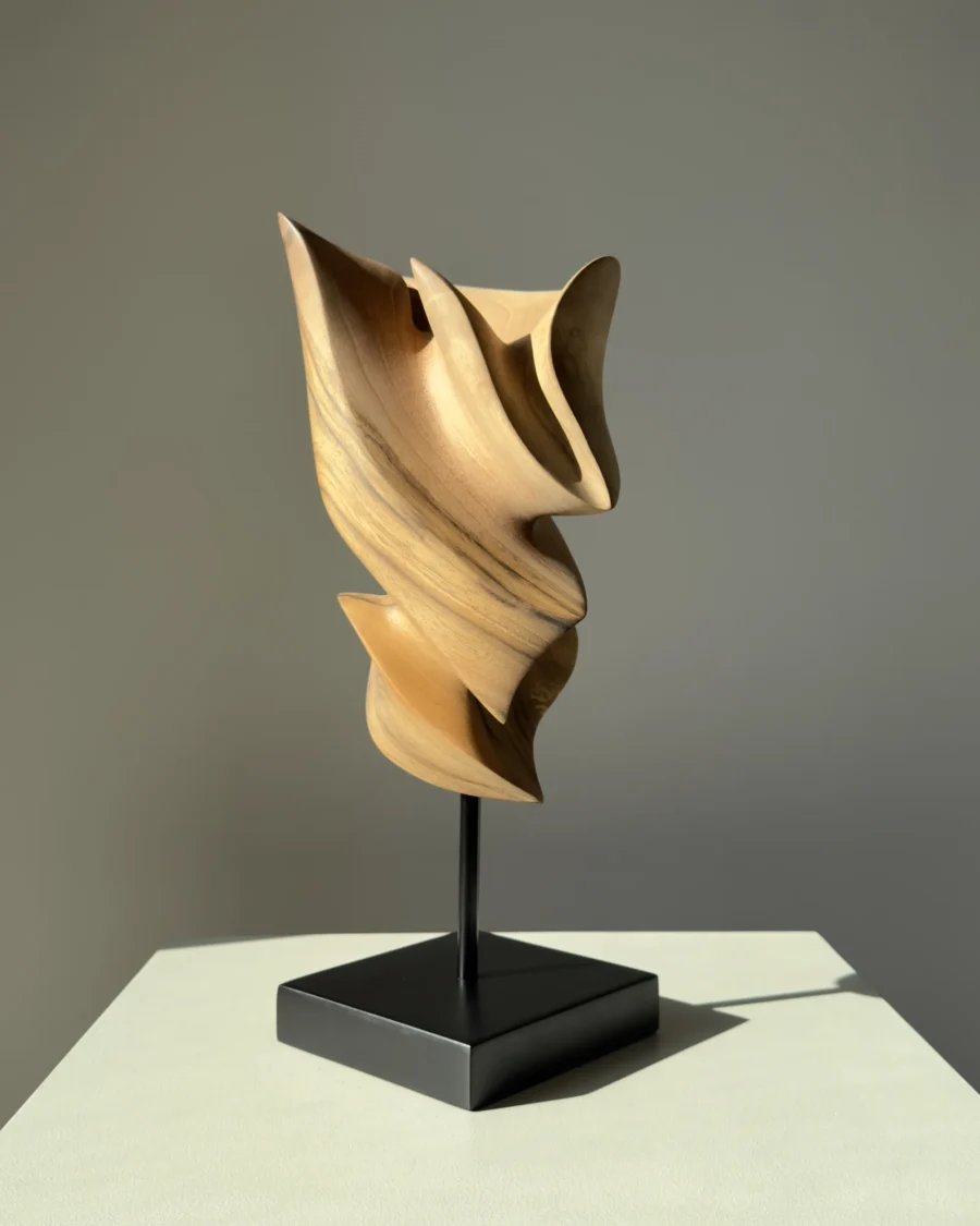 Breath of Fire hand-carved walnut wood sculpture displayed in natural sunlight on a black beechwood base
