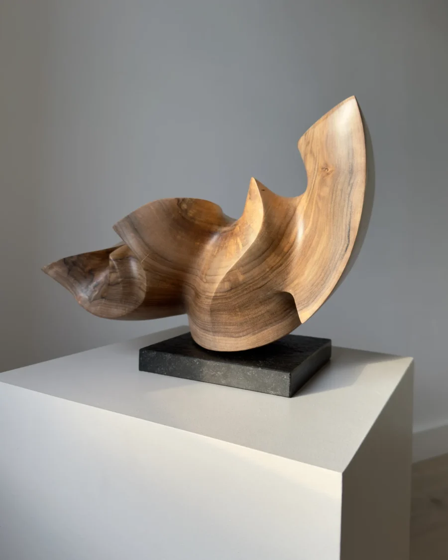 confluence-walnut-sculpture-closeup-black-granite-base Front view of Confluence abstract walnut wood sculpture on a black granite base.