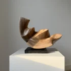 confluence-wood-sculpture-side-profile-walnut-art Profile view of Confluence abstract walnut sculpture on a black granite base in natural light.