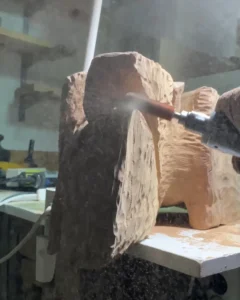 Wood dust rising during the early shaping of an abstract sculpture.