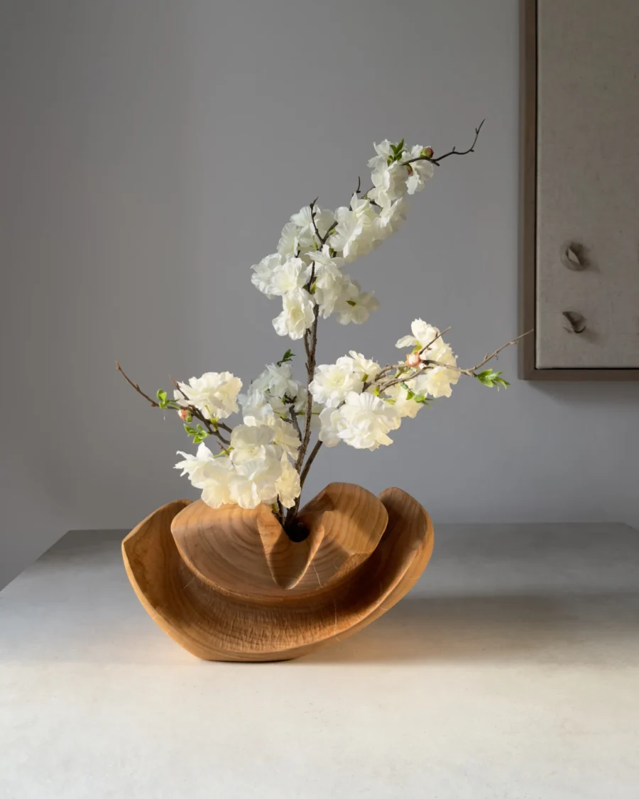 Memory Lines hand-carved cherry wood ikebana vase displayed with flowering branch in a contemporary interior