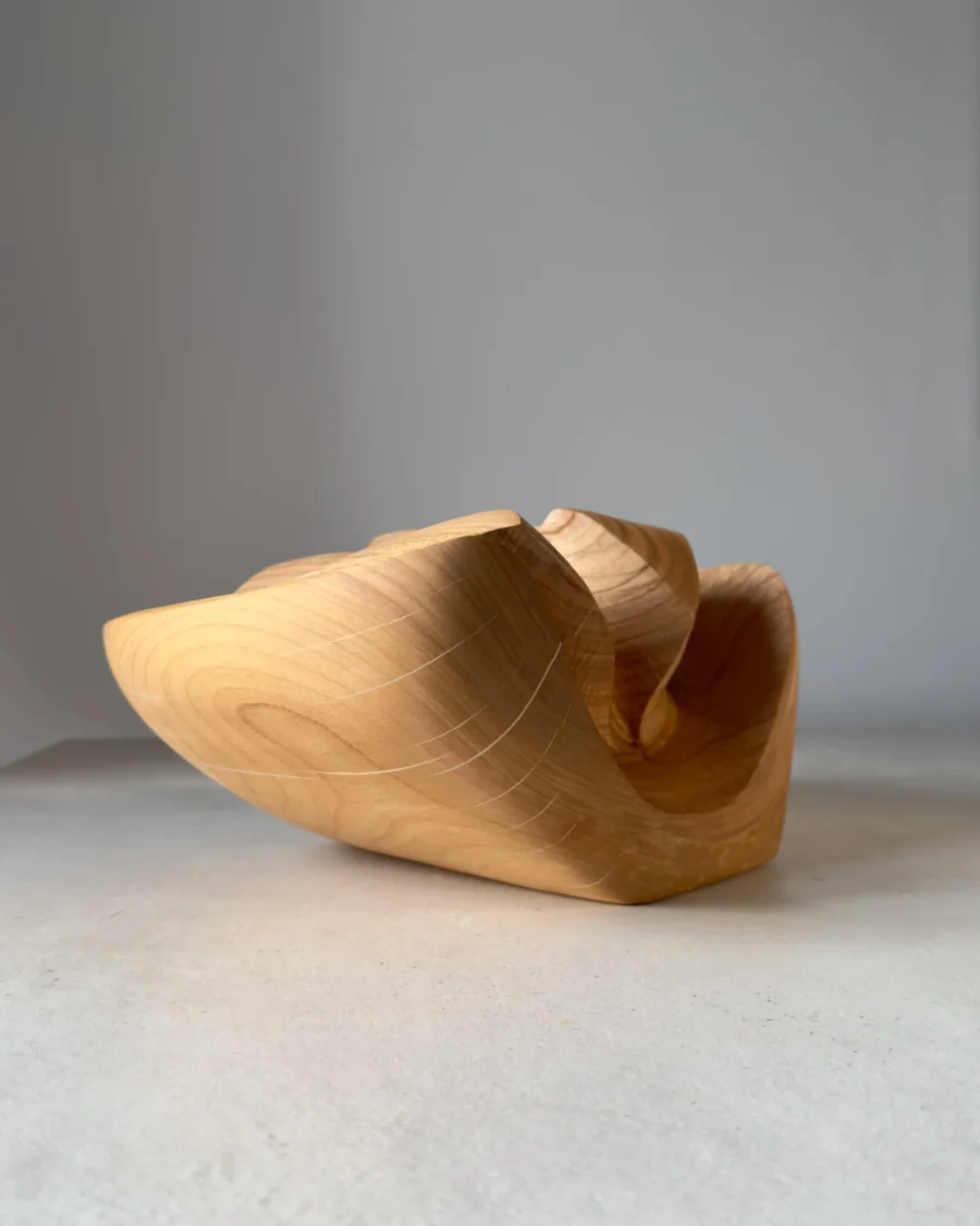 Detail of preserved natural cracks and flowing grain on hand-carved cherry wood sculpture vase