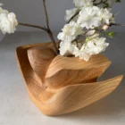 Cherry wood ikebana vase with flowering branch arrangement in natural light
