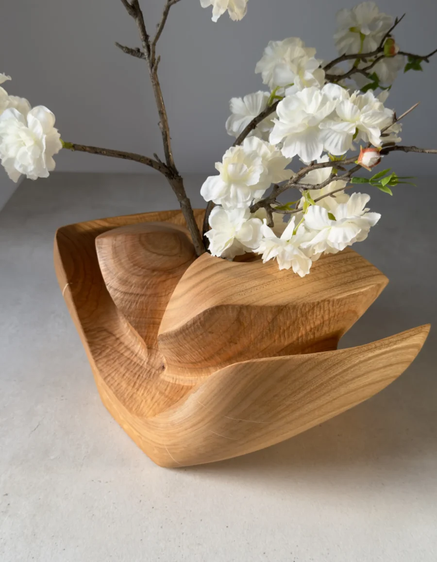 Cherry wood ikebana vase with flowering branch arrangement in natural light