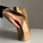 Hand carved walnut sculpture Quiet Endurance displayed in hands from the side viev