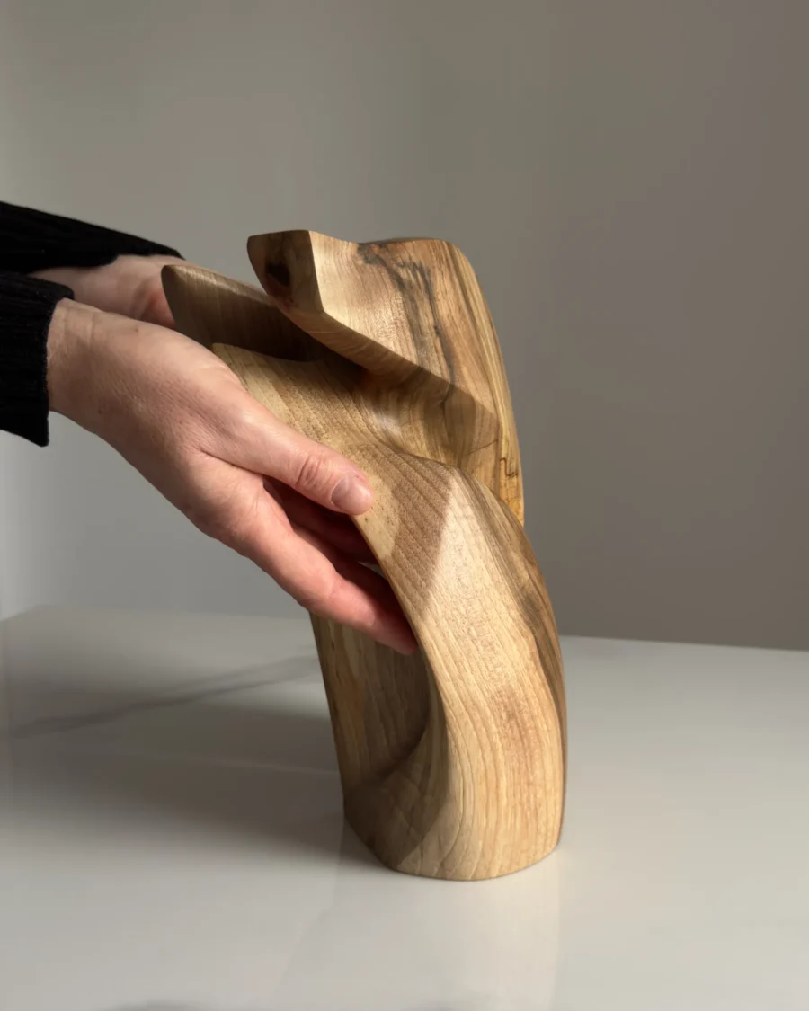 Hand carved walnut sculpture Quiet Endurance displayed in hands from the side viev
