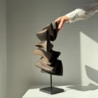 Abstract apple wood sculpture Shaped by Silence displayed in natural sunlight on a granite base.