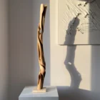 silent-axis-sculpture-profile-shadow Profile view of Silent Axis abstract walnut sculpture casting a dramatic shadow in natural sunlight