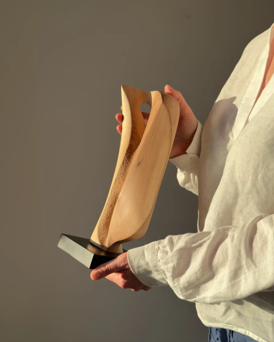 Veil of Air apple wood sculpture held in hands in warm natural light