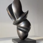 Hand-carved abstract apple wood sculpture "Poise" viewed from the front, showing its balanced organic form on a black granite base.