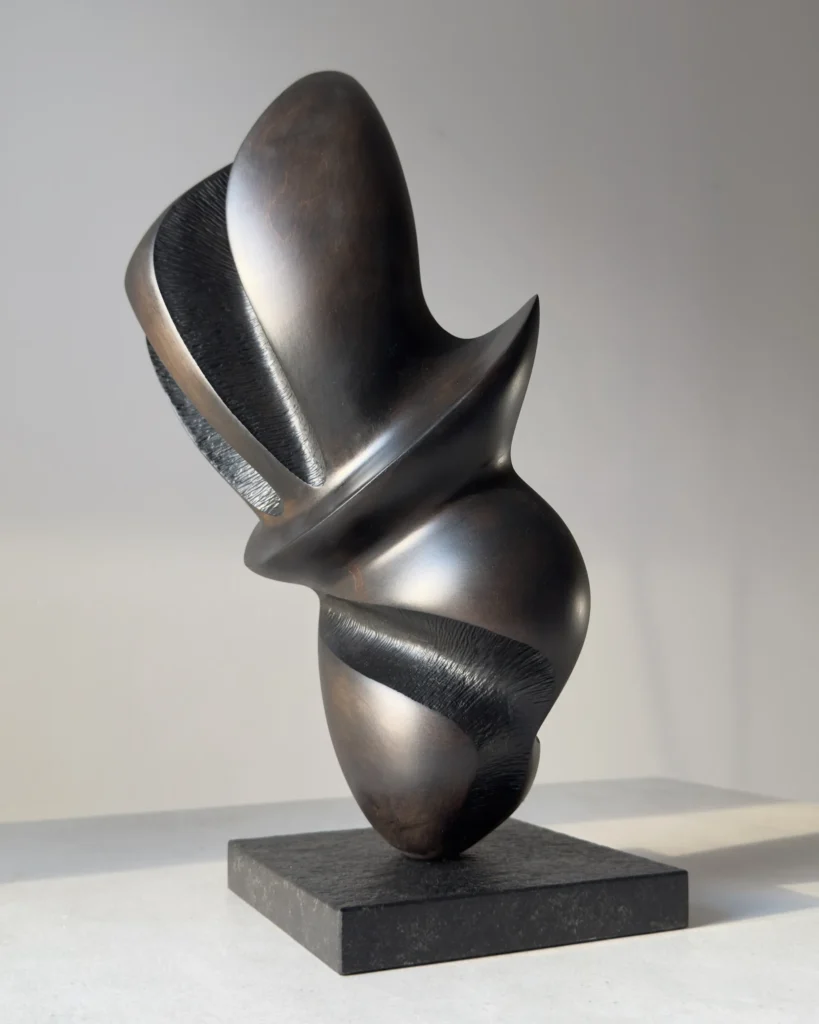 Hand-carved abstract apple wood sculpture "Poise" viewed from the front, showing its balanced organic form on a black granite base.
