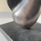 Detail of the black granite base and stainless steel rod supporting the hand-carved sculpture "Poise".