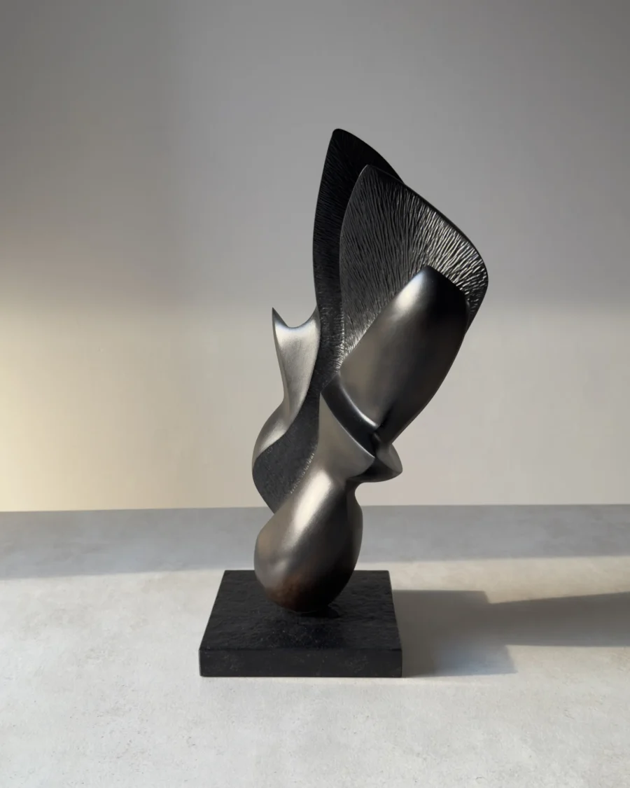Side profile of the hand-carved apple wood sculpture "Poise", highlighting its sculptural balance and contrasting smooth and textured surfaces.