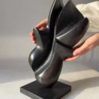 Hand holding the original apple wood sculpture "Poise", showing its scale, craftsmanship, and natural matte finish.