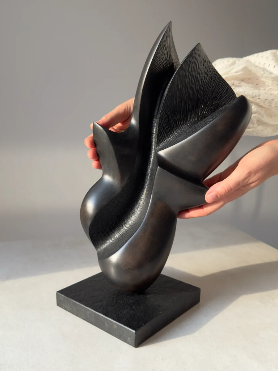 Hand holding the original apple wood sculpture "Poise", showing its scale, craftsmanship, and natural matte finish.