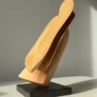 Left side view of the hand-carved apple wood sculpture revealing the relationship between solid form and open space.
