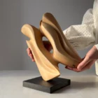 Hand-carved apple wood sculpture "Sway" shown in scale, mounted on a black granite base.