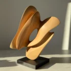 Side view of the one-of-a-kind hand-carved apple wood sculpture "Sway" on a black granite base in natural light.