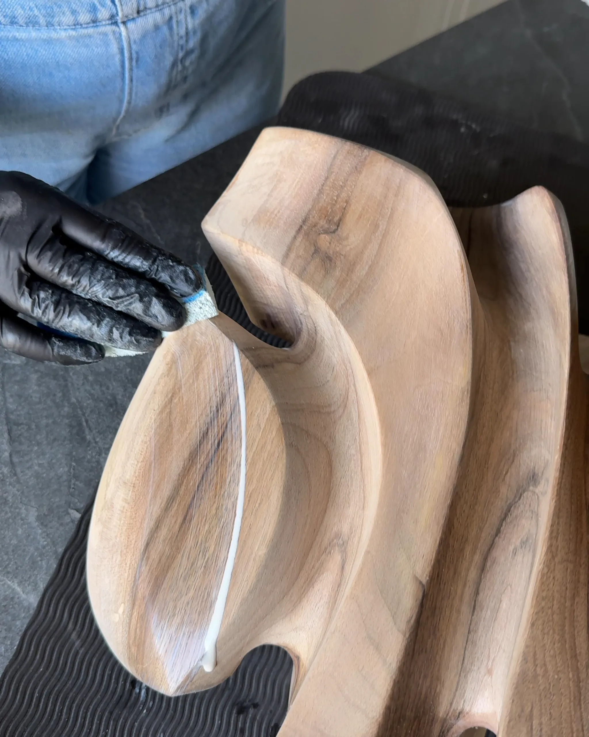 Applying hardwax oil to a hand-carved walnut sculpture to reveal the depth of the wood grain.