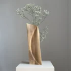 continuum-abstract-walnut-vase-curved-line-flowers Side view of Continuum hand-carved walnut vase with fresh white flowers, showing its tall slender profile and rounded edge.