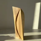 Front view of Continuum showing the long curved line carved into one plane of the natural walnut form.