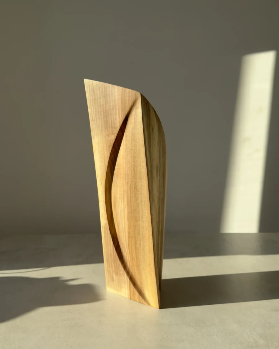 Front view of Continuum showing the long curved line carved into one plane of the natural walnut form.