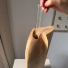 Hand placing the removable glass tube inside the opening of the Continuum walnut sculptural vase.