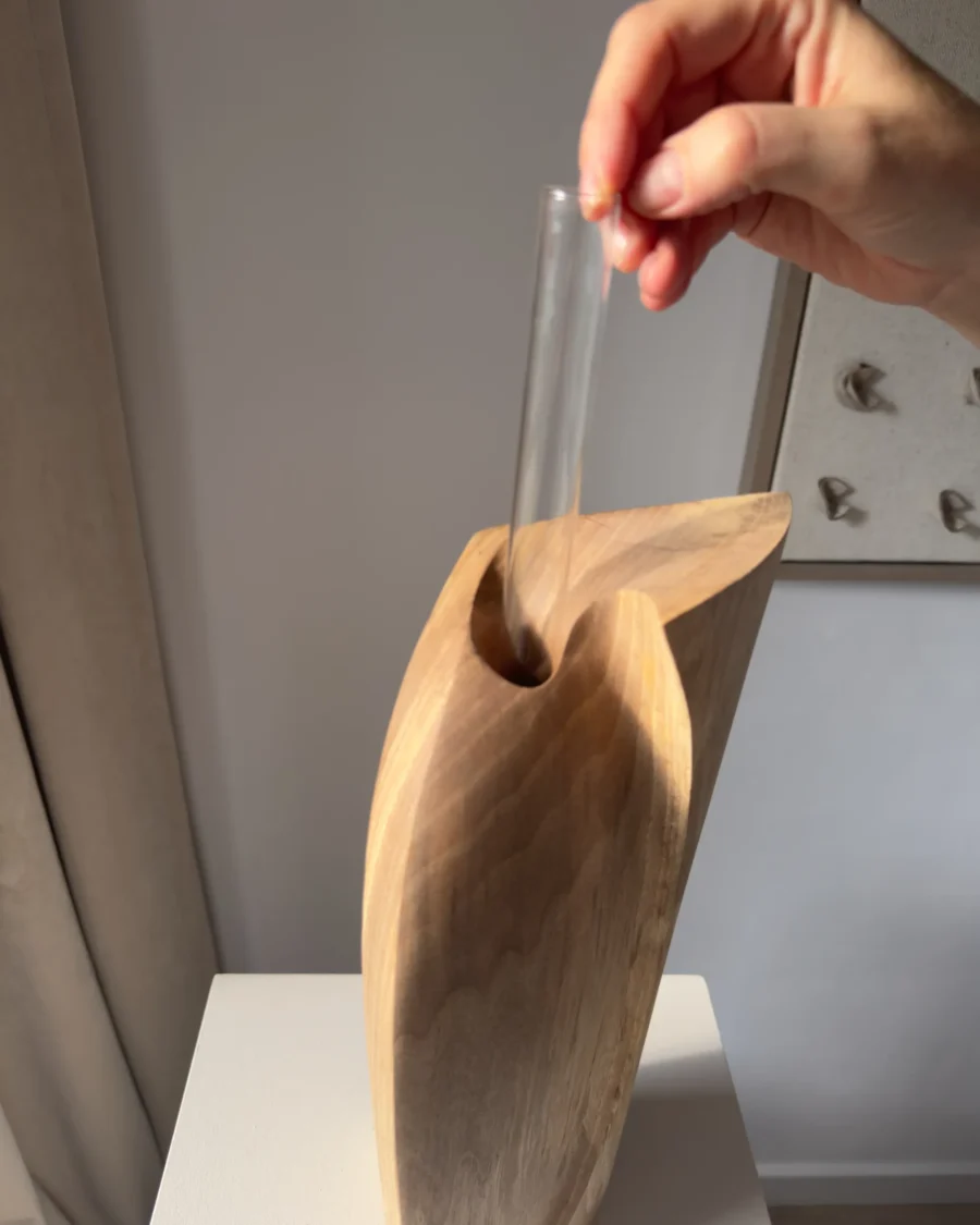 Hand placing the removable glass tube inside the opening of the Continuum walnut sculptural vase.