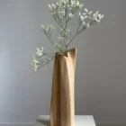 continuum-walnut-sculptural-vase-fresh-flowers-front Continuum hand-carved walnut sculptural vase with delicate fresh white flowers, shown from the front on a white pedestal