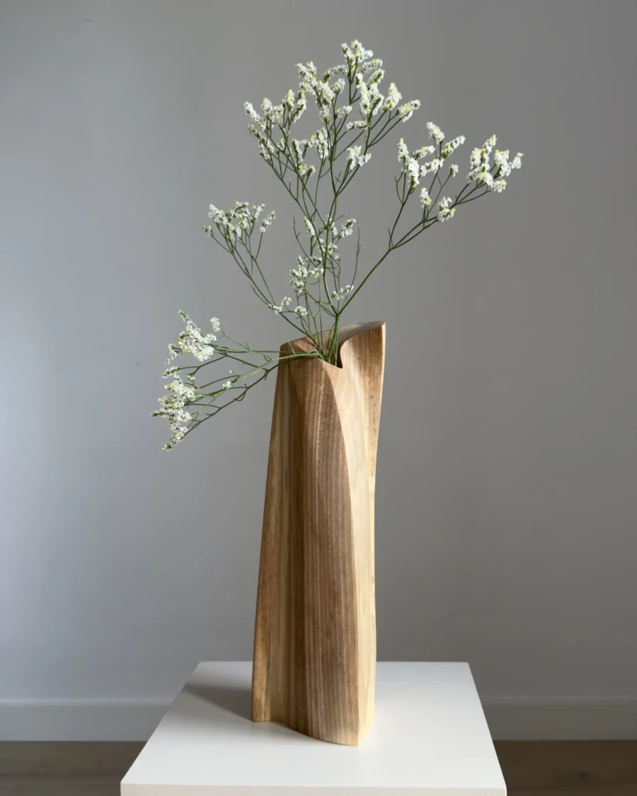 continuum-walnut-sculptural-vase-fresh-flowers-front Continuum hand-carved walnut sculptural vase with delicate fresh white flowers, shown from the front on a white pedestal