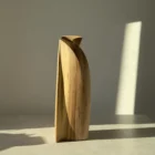 Rear three-quarter view of Continuum showing a deep curved plane and the natural walnut grain in sunlight