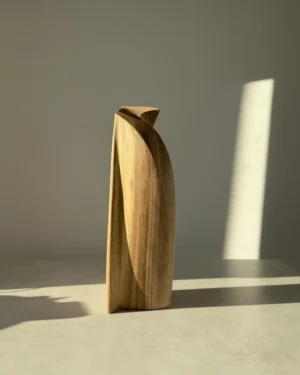 Rear three-quarter view of Continuum showing a deep curved plane and the natural walnut grain in sunlight