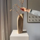 Hand arranging delicate branches in the Continuum walnut sculpture, demonstrating its use as a vase.