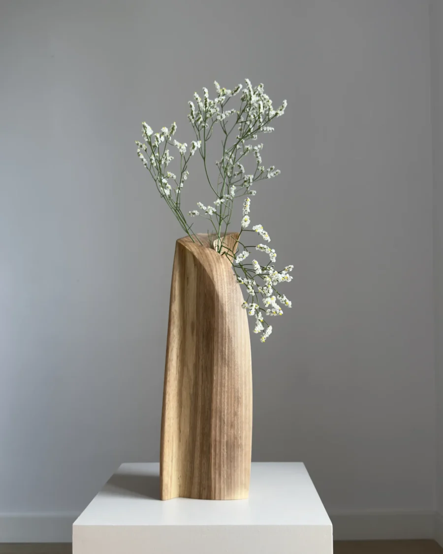 continuum-walnut-vase-side-view-fresh-flowers Continuum abstract walnut vase with fresh white flowers, showing the carved curved line across the front plane.
