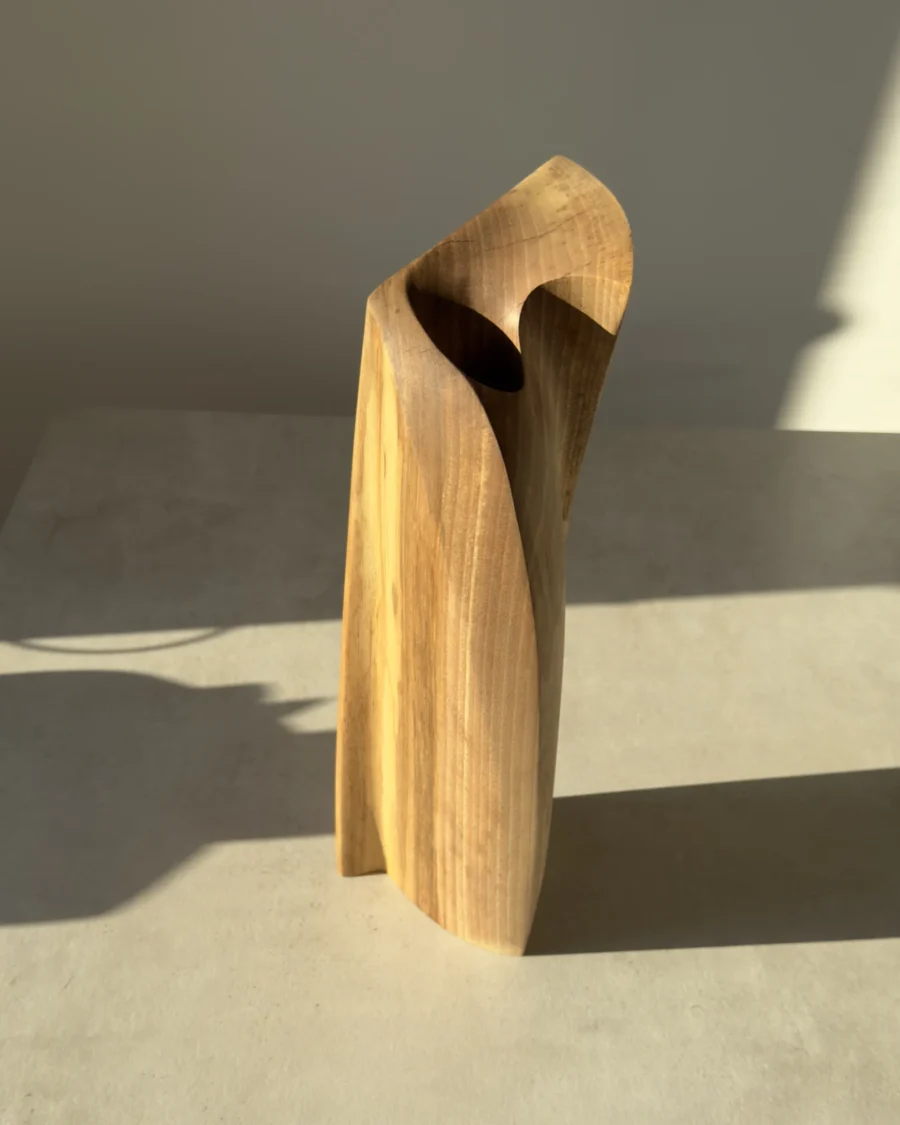 Elevated view of the Continuum walnut sculpture revealing the sculpted top and deep opening for a glass tube