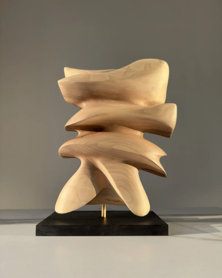 Back view of Fluens highlighting smooth layered planes, flowing silhouette and natural walnut texture.