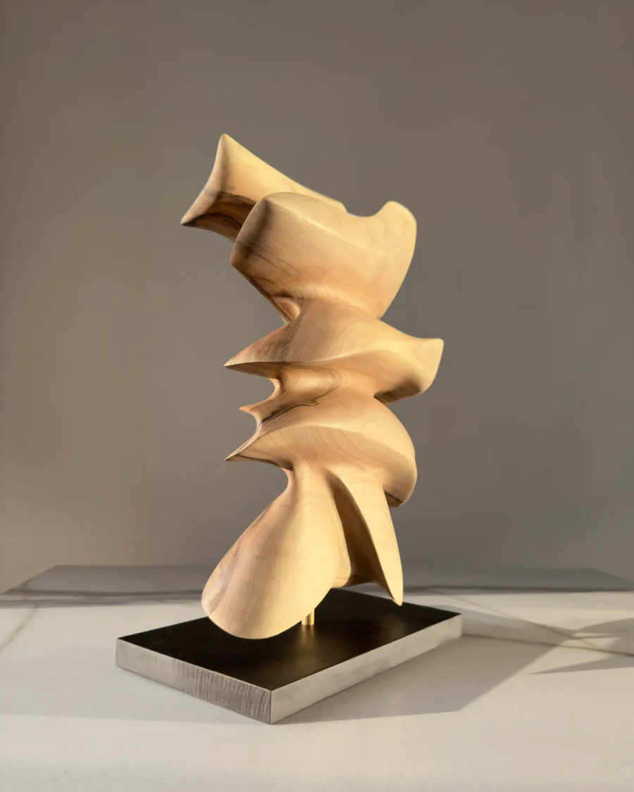 Rear view of Fluens, showcasing the continuous organic form and hand-carved walnut surfaces.