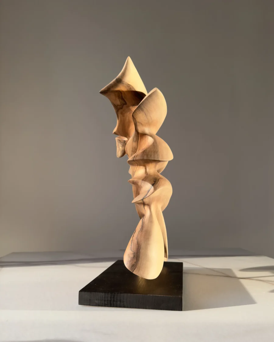 Side profile of Fluens revealing sculptural depth, flowing contours and the natural walnut grain.