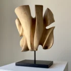 Left-side view of Folded Presence abstract walnut sculpture on a polished black granite base.