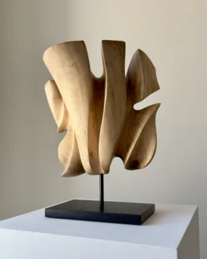 Left-side view of Folded Presence abstract walnut sculpture on a polished black granite base.