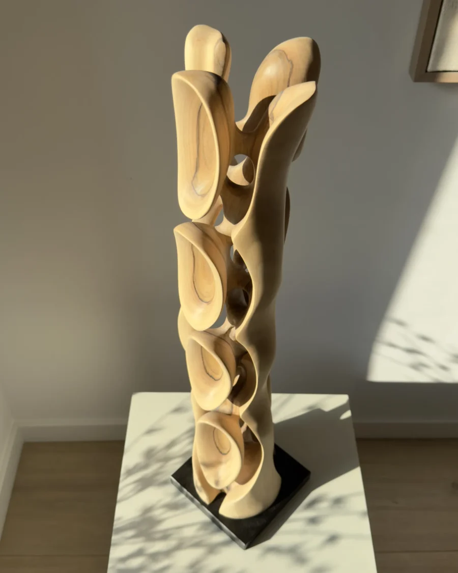 Three-quarter view of Ivory Flow, a hand-carved walnut sculpture photographed in warm natural light.