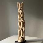 Side view of Ivory Flow revealing the flowing silhouette and open structure of the hand-carved walnut sculpture.